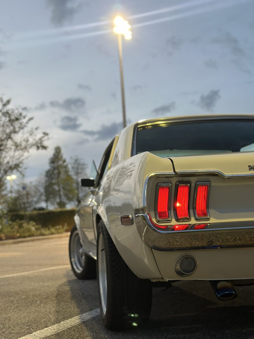 The Mustang's red taillights glowing in a parking lot at dusk